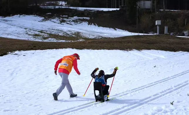 A coach cheers on Anja Wicker, of Germany, during the cross country skiing women's 10Km interval start sitting final at the 2026 Winter Paralympics, in Tesero, Italy, Wednesday, March 11, 2026. (AP Photo/Evgeniy Maloletka)