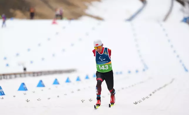 Wang Chenyang, of China, crosses the finish line in the cross country skiing men's 10Km interval start classic standing final at the 2026 Winter Paralympics, in Tesero, Italy, Wednesday, March 11, 2026. (AP Photo/Evgeniy Maloletka)