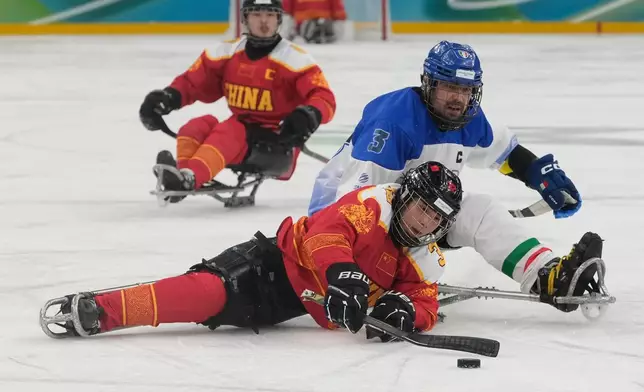 Chine's Li Hongguan challenges for the puck with Italy's Gianluigi Rosa during the Group A hockey match between Italy and China at the 2026 Winter Paralympics, in Milan, Italy, Monday, March 9, 2026. (AP Photo/Luca Bruno)