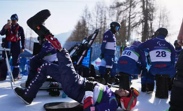 Mike Schultz, of the United States, stretches during warmup before the start of the snowboard cross competitions at the 2026 Winter Paralympics, in Cortina d'Ampezzo, Italy, Sunday, March 8, 2026. (AP Photo/Evgeniy Maloletka