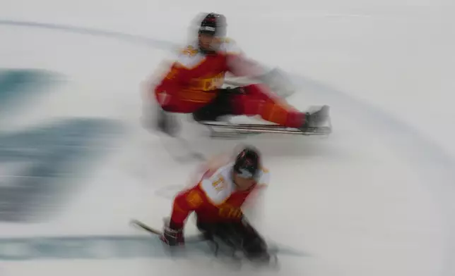 China's Zhanfu Zhu, top, and China's Yifeng Shen control the puck during the Group A hockey match between China and Germany at the 2026 Winter Paralympics, in Milan, Italy, Saturday, March 7, 2026. (AP Photo/Antonio Calanni)
