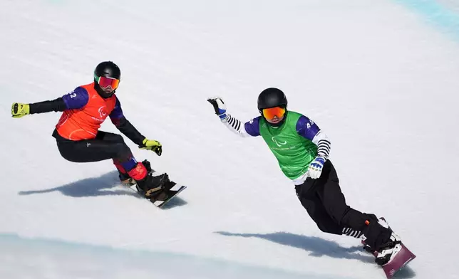Lee Jehyuk, of South Korea, and Sun Qi, of China, left, compete in a men's snowboard cross SB-LL2 quarterfinal at the 2026 Winter Paralympics, in Cortina d'Ampezzo, Italy, Sunday, March 8, 2026. (AP Photo/Evgeniy Maloletka