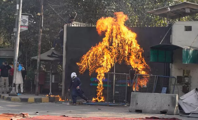 Shiite Muslims set a fire at the U.S. Consulate's entrance gate during a rally to condemn the killing of Iranian Supreme Leader Ayatollah Ali Khamenei, in Lahore, Pakistan, Sunday, March 1, 2026. (AP Photo/K.M. Chaudary)