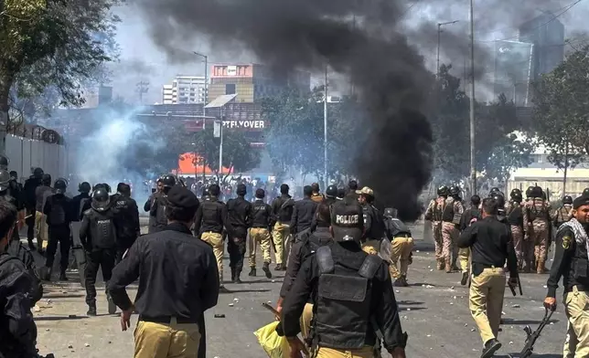 Police officers chase Shiite Muslims blocking a road and set on fire tires during a protest over the killing of Iranian Supreme Leader Ayatollah Ali Khamenei, in Karachi, Pakistan, Sunday, March 1, 2026. (AP Photo/Muhammad Farooq)