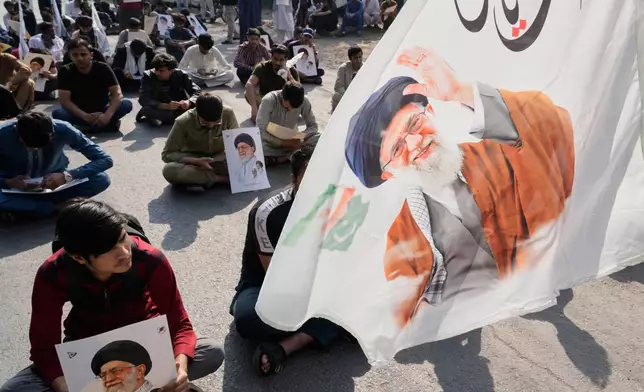 Pakistani Shiite Muslims sit on a road during a demonstration to condemn the death of Iranian Supreme Leader Ayatollah Ali Khamenei in a major attack by Israel and the United States, in Lahore, Pakistan, Sunday, March 1, 2026. (AP Photo/K.M. Chaudary)