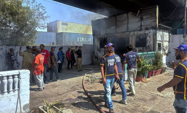Police officers and rescue workers examine a burnt police post, which was set on fire by angry protestors close to the U.S. Consulate following protesters stormed the U.S. Consulate in Karachi, Pakistan, Sunday, March 1, 2026. (AP Photo/Muhammad Farooq)