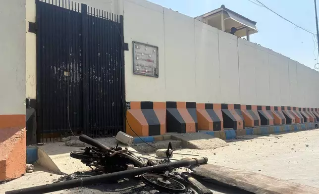 A security officer takes position as a motorcycle which was set on fire by angry protestors is seen outside the U.S. Consulate following protesters stormed the U.S. Consulate in Karachi, Pakistan, Sunday, March 1, 2026. (AP Photo/Muhammad Farooq)
