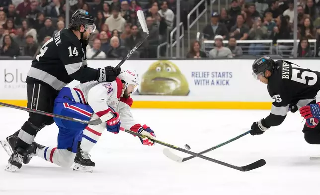 Montréal Canadiens center Phillip Danault, center, tries to shoot the puck while under pressure from Los Angeles Kings right wing Alex Laferriere, left, and right wing Quinton Byfield during the second period of an NHL hockey game Saturday, March 7, 2026, in Los Angeles. (AP Photo/Mark J. Terrill)