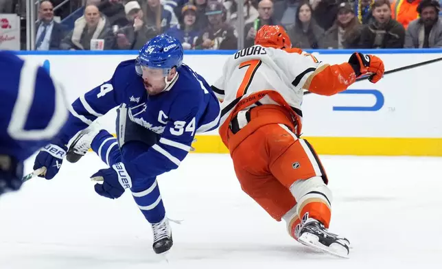 Toronto Maple Leafs Auston Matthews (34) is injured by Anaheim Ducks Radko Gudas (7) during the second period of an NHL hockey game in Toronto, Thursday, March 12, 2026. (Nathan Denette/The Canadian Press via AP)