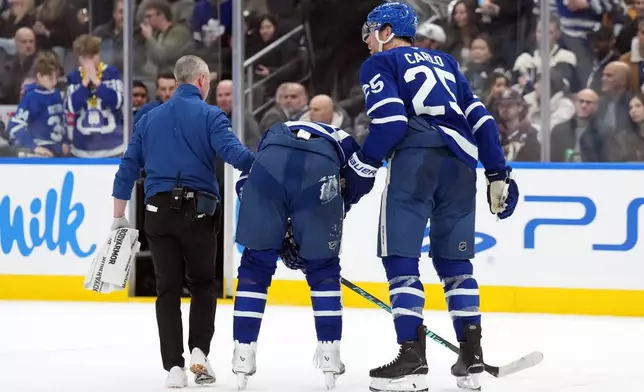 Toronto Maple Leafs Auston Matthews, center, is helped off the ice after being injured by Anaheim Ducks Radko Gudas during the second period of an NHL hockey game in Toronto, Thursday, March 12, 2026. (Nathan Denette/The Canadian Press via AP)
