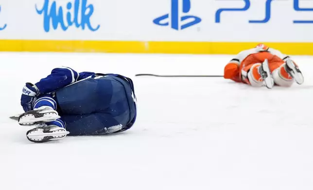Toronto Maple Leafs Auston Matthews (34) and Anaheim Ducks Radko Gudas (7) lay on the ice after colliding during second period NHL hockey action in Toronto on Thursday, March 12, 2026. (Nathan Denette/The Canadian Press via AP)