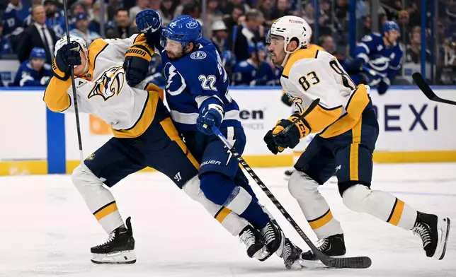 Tampa Bay Lightning right wing Oliver Bjorkstrand (22) races for the puck against Nashville Predators right wing Matthew Wood (71) and defenseman Adam Wilsby (83) during the second period of an NHL hockey game, Sunday, March 29, 2026, in Tampa, Fla. (AP Photo/Jason Behnken)