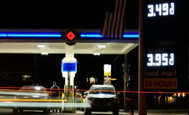 Vehicles drive past a gas station as a person puts gasoline in a vehicle on Sunday, March 8, 2026, in Portland, Ore. (AP Photo/Jenny Kane)