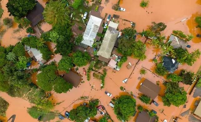 An aerial view of homes surrounded by floodwaters in Waialua, Hawaii, Friday, March 20, 2026. (AP Photo/Mengshin Lin)