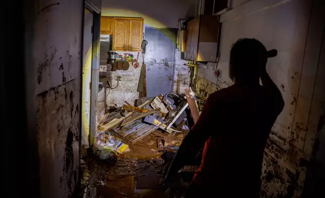Glenn Duquez, associate pastor at the Church of God Jesus is Alive Fellowship, shines a flashlight into a mud-riddled kitchen after the fast-moving flood in Haleiwa, Hawaii Saturday, March 21, 2026. (Stephen Lam/San Francisco Chronicle via AP)