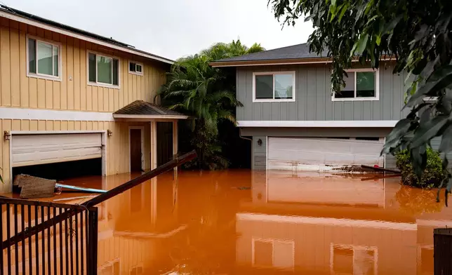 Floodwaters fill the ground level of homes in Waialua, Hawaii, Friday, March 20, 2026. (AP Photo/Mengshin Lin)