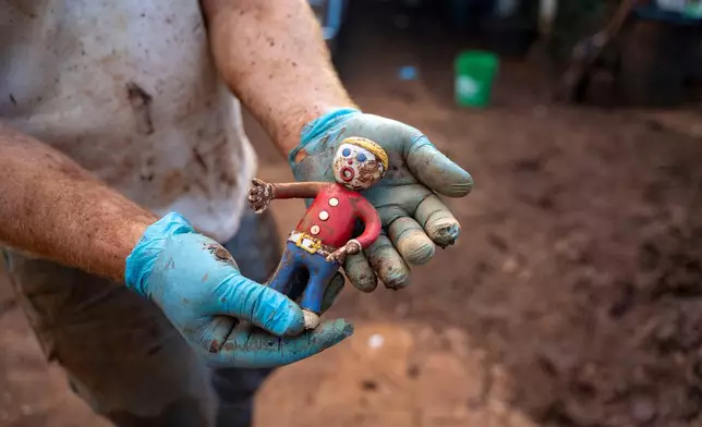 Nate Knaggs holds a mud-covered Mr. Bill toy he recovered from flood debris at his home, Tuesday, March 24, 2026, in Haleiwa, Hawaii. (AP Photo/Mengshin Lin)