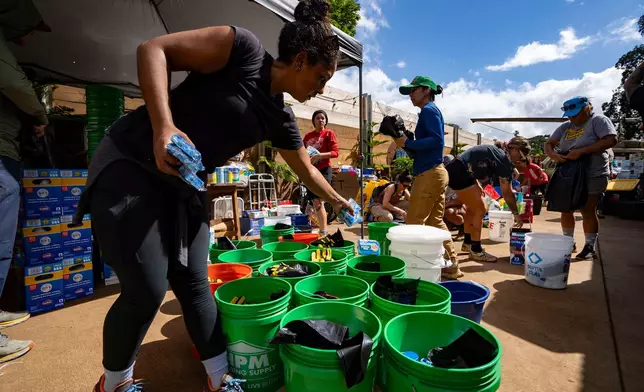 Volunteers sort donated supplies for distribution at Haleiwa Distillery following recent flooding, Tuesday, March 24, 2026, in Waialua, Hawaii. (AP Photo/Mengshin Lin)