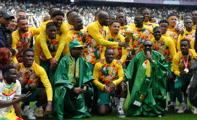 Singer Youssou N'dour, bottom row third left, celebrates with the Senegal team ahead of the international friendly soccer match between Senegal and Peru in Saint-Denis, outside of Paris, Saturday, March 28, 2026. (AP Photo/Aurelien Morissard)