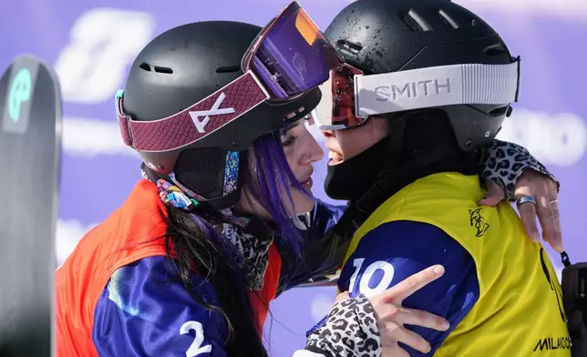 Brenna Huckaby, of the United States, left, embraces Eri Sakashita, of Japan, after finishing 6th in the women's snowboard cross SB-LL2 at the 2026 Winter Paralympics, in Cortina d'Ampezzo, Italy, Sunday, March 8, 2026. (AP Photo/Emilio Morenatti)