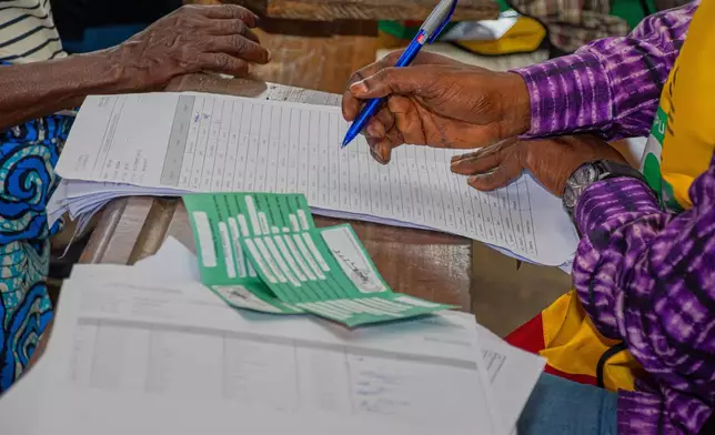 An election official check for the name of a voter in a register at a polling station in Brazzaville, the Republic of Congo, Sunday, March 15, 2026. (AP Photo/Vivace Mambouana)