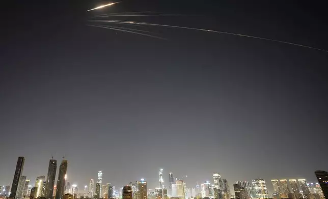 Missiles launched from Iran streak across the sky over central Israel, Wednesday, March 18, 2026. (AP Photo/Ohad Zwigenberg)