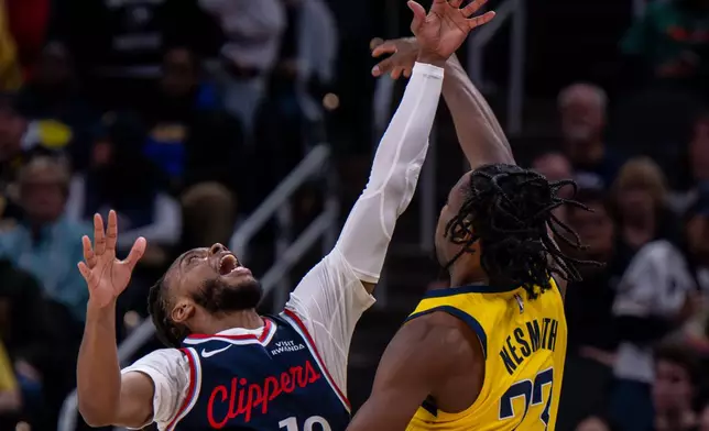 Los Angeles Clippers guard Darius Garland (10) reaches to block a pass by Indiana Pacers guard Aaron Nesmith (23) during the first half of an NBA basketball game in Indianapolis, Friday, March 27, 2026. (AP Photo/Doug McSchooler)