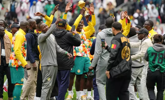 Senegal players celebrate with the Africa Cup of Nations trophy ahead of the international friendly soccer match between Senegal and Peru in Saint-Denis, outside of Paris, Saturday, March 28, 2026. (AP Photo/Aurelien Morissard)