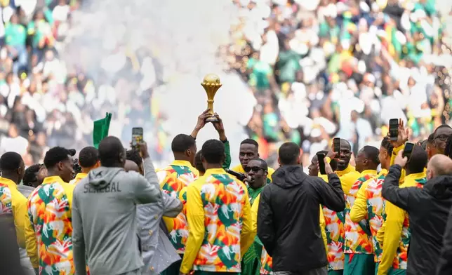 Senegal players celebrate with the Africa Cup of Nations trophy ahead of the international friendly soccer match between Senegal and Peru in Saint-Denis, outside of Paris, Saturday, March 28, 2026. (AP Photo/Aurelien Morissard)