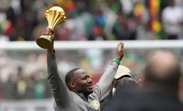 Senegal coach Pape Thiaw holds the Africa Cup of Nations trophy ahead of the international friendly soccer match between Senegal and Peru in Saint-Denis, outside of Paris, Saturday, March 28, 2026. (AP Photo/Aurelien Morissard)