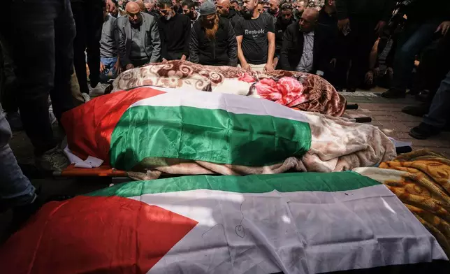 Palestinian men pray during the funeral of three Palestinian women who were killed in an Iranian strike in the West Bank village of Beit Awa, near Hebron, Thursday, March 19, 2026. (AP Photo/Mahmoud Illean)
