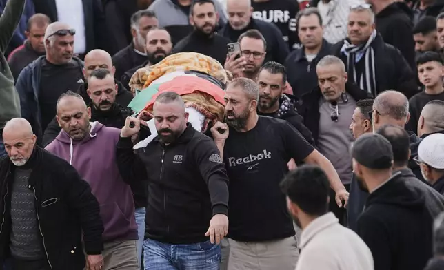 Palestinians carry the body of Palestinian woman who killed in an Iranian strike, in the West Bank village of Beit Awa, near Hebron, Thursday, March 19, 2026. (AP Photo/Mahmoud Illean)