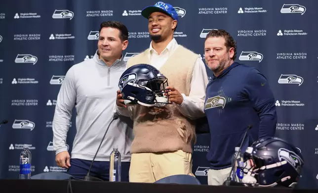 Seattle Seahawks head coach Mike Macdonald, from left, wide receiver Jaxon Smith-Njigba (11), and general manager John Schneider, pose for a photo during an NFL football news conference on Wednesday, March 25, 2026, in Seattle. (AP Photo/Kevin Ng)