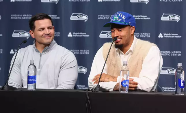 Seattle Seahawks wide receiver Jaxon Smith-Njigba, right, speaks as head coach Mike Macdonald listensduring an NFL football news conference on Wednesday, March 25, 2026, in Seattle. (AP Photo/Kevin Ng)