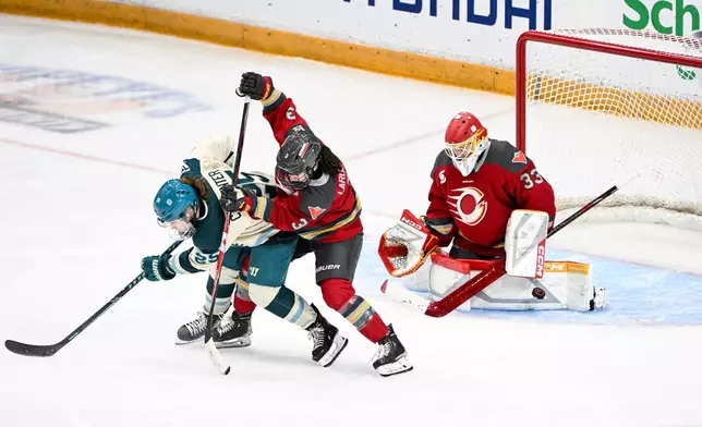 Ottawa Charge's Jocelyne Larocque (3) ties up Seattle Torrent's Alex Carpenter (25) as Ottawa Charge goaltender Gwyneth Philips (33) blocks a shot from the point during the third period PWHL hockey game in Ottawa, on Wednesday, March 4, 2026. (Spencer Colby/The Canadian Press via AP)