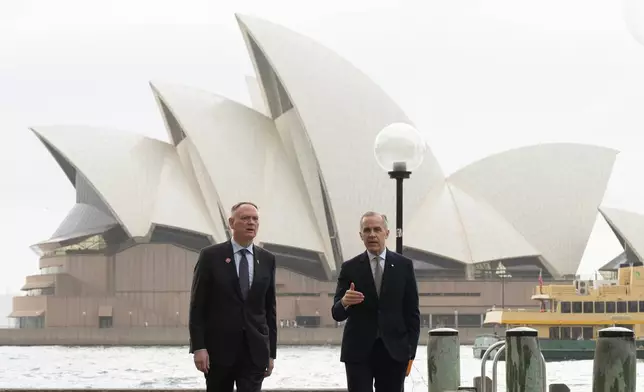 Canada's Defence Minister David McGuinty, left, talks with Canada's Prime Minister Mark Carney as they walk to a news conference, in Sydney, Australia, Wednesday, March 4, 2026. (Adrian Wyld/The Canadian Press via AP)