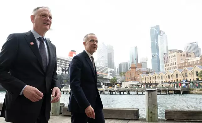 Canadian Defence Minister David McGuinty talks with Canadian Prime Minister Mark Carney as they walk to a news conference in Sydney, Australia, Wednesday, March 4, 2026 in Sydney. (Adrian Wyld/The Canadian Press via AP)