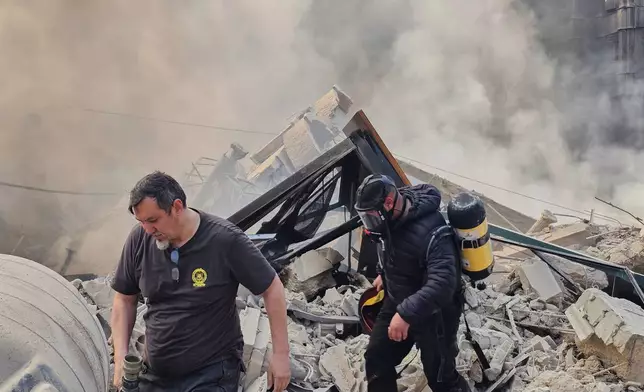Firefighters inspect the rubble as smoke rises from a building hit by an Israeli airstrike in Dahiyeh, a southern suburb of Beirut, Lebanon, Tuesday, March 3, 2026. (AP Photo/Hassan Ammar)
