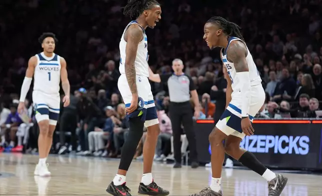 Minnesota Timberwolves guards Bones Hyland (8), middle, and Ayo Dosunmu (13), right, celebrate during a timeout in the first half of an NBA basketball game against the Utah Jazz, Wednesday, March 18, 2026, in Minneapolis. (AP Photo/Abbie Parr)