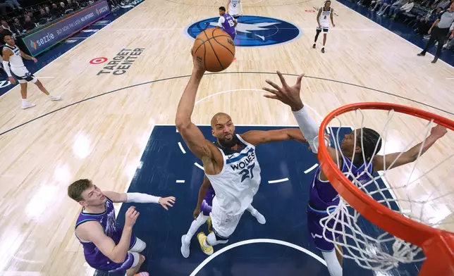Minnesota Timberwolves center Rudy Gobert (27) dunks while defended by Utah Jazz forwards Kyle Filipowski (22), left, and Cody Williams (5), right, during the first half of an NBA basketball game, Wednesday, March 18, 2026, in Minneapolis. (AP Photo/Abbie Parr)