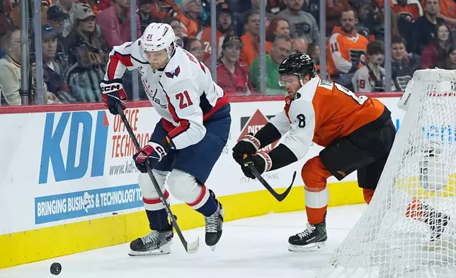 Washington Capitals' Aliaksei Protas (21) tries to keep the puck from Philadelphia Flyers' Cam York (8) during the first period of an NHL hockey game, Wednesday, March 11, 2026, in Philadelphia. (AP Photo/Matt Rourke)