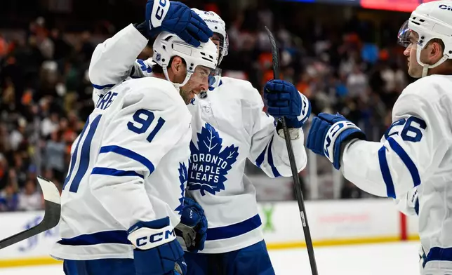 Toronto Maple Leafs center John Tavares (91) is greeted by teammates after scoring the game-winning goal during overtime of an NHL hockey game against the Anaheim Ducks, Monday, March 30, 2026, in Anaheim, Calif. (AP Photo/William Liang)