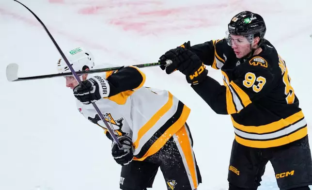 Boston Bruins center Fraser Minten (93) hits Pittsburgh Penguins center Connor Dewar with his stick during the first period of an NHL hockey game, Tuesday, March 3, 2026, in Boston. (AP Photo/Charles Krupa)