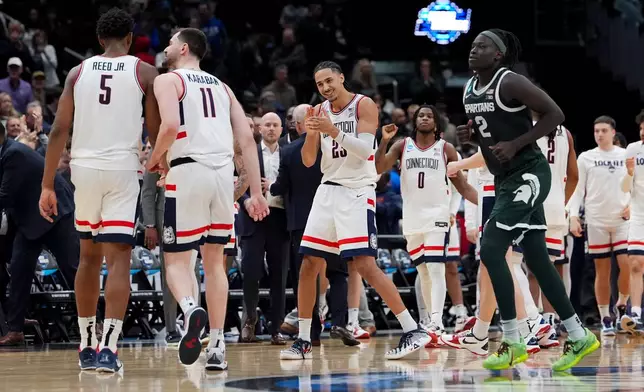 UConn forward Jayden Ross (23) celebrates with forward Tarris Reed Jr. (5) and forward Alex Karaban (11) against Michigan State during the second half in the Sweet 16 of the NCAA college basketball tournament, Saturday, March 28, 2026, in Washington. (AP Photo/Stephanie Scarbrough)