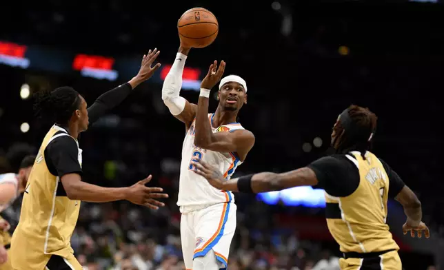 Oklahoma City Thunder guard Shai Gilgeous-Alexander (2) looks to pass the ball against Washington Wizards guards Jamir Watkins, right, and Bub Carrington, left, during the first half of an NBA basketball game, Saturday, March 21, 2026, in Washington. (AP Photo/Nick Wass)