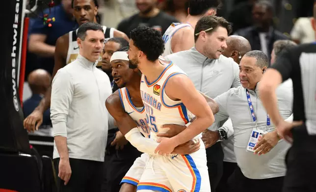 Oklahoma City Thunder guard Shai Gilgeous-Alexander, center left, grabs teammate guard Ajay Mitchell (25) after a scuffle with the Washington Wizards during the first half of an NBA basketball game, Saturday, March 21, 2026, in Washington. (AP Photo/Nick Wass)
