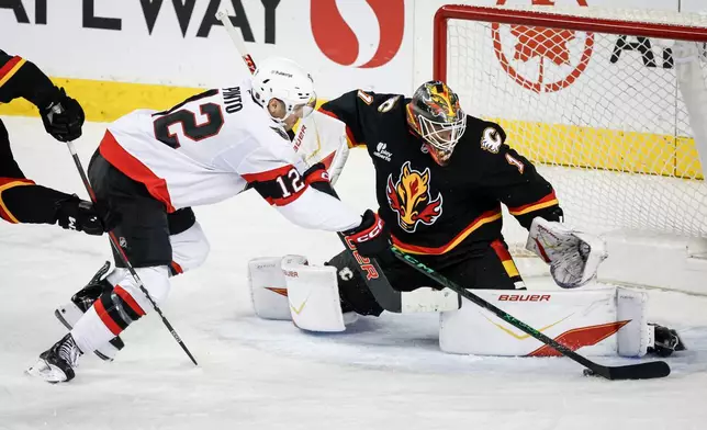 Ottawa Senators' Shane Pinto, left, has his shot stopped by Calgary Flames goalie Devin Cooley during the third period of an NHL hockey game in Calgary on Thursday, March 5, 2026. (Jeff McIntosh/The Canadian Press via AP)