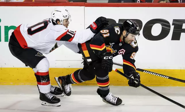 Ottawa Senators' Jordan Spence, left, checks Calgary Flames' Nazem Kadri during the third period of an NHL hockey game in Calgary, Alberta, Thursday, March 5, 2026. (Jeff McIntosh/The Canadian Press via AP)