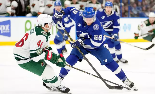 Minnesota Wild defenseman Jared Spurgeon (46) knocks the puck away from Tampa Bay Lightning center Jake Guentzel (59) during the second period of an NHL hockey game Tuesday, March 24, 2026, in Tampa, Fla. (AP Photo/Chris O'Meara)