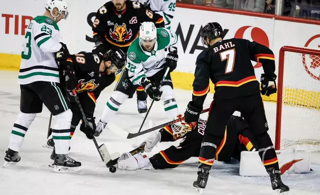 Dallas Stars' Mavrik Bourque (22) looks on as Calgary Flames goalie Devin Cooley dives for the puck during the third period of an NHL hockey game in Calgary, Alberta on Tuesday, March 3, 2026. (Jeff McIntosh/The Canadian Press via AP)